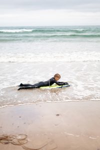 child surfing on a body board on a Norfolk beach during a family photoshoot