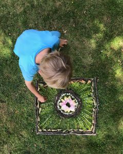 child making paterns and artwork from leaves, stones and petals