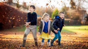 children throwing leaves and having fun on an Autumn photography shoot in Saffron walden