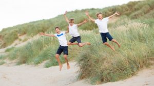 brothers jumping off sand dunes during a family photoshoot in north norfolk