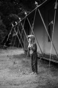 boy leaning on te ropes of a tent during a glamping trip in Norfolk