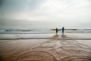 Children running into the sea at Thornha in Norfolk on a grey summer day