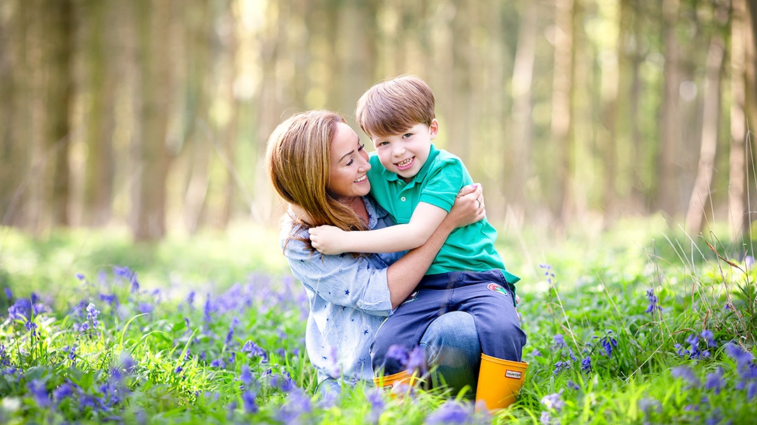 mother and son embracing during a photoshoot in a bluebell wood in Cambridge