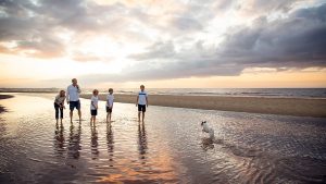 family enjoying a photo shoot at Brancaster beach with their dog at sunset