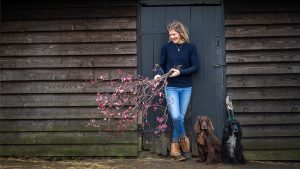 Amelia Cornish Floral design stading outside her barn studio wiht spring blossom twigs during a personal branding photoshoot in saffron walden