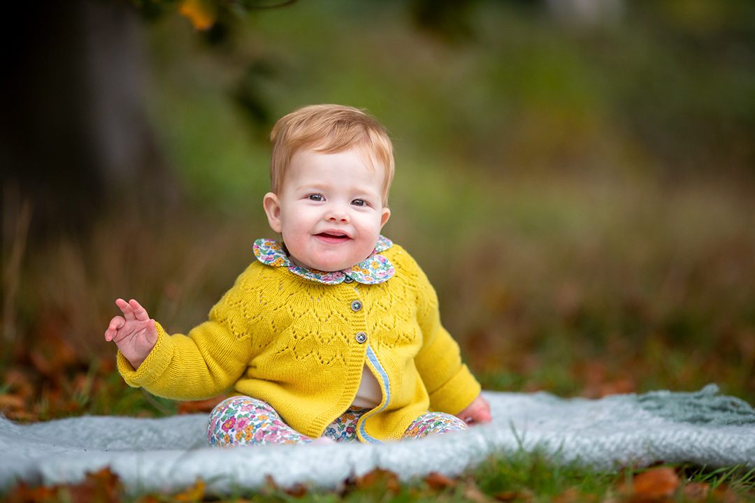 baby girl in a yellow cardigan in an autumn photo by cambridge photographer louisa french